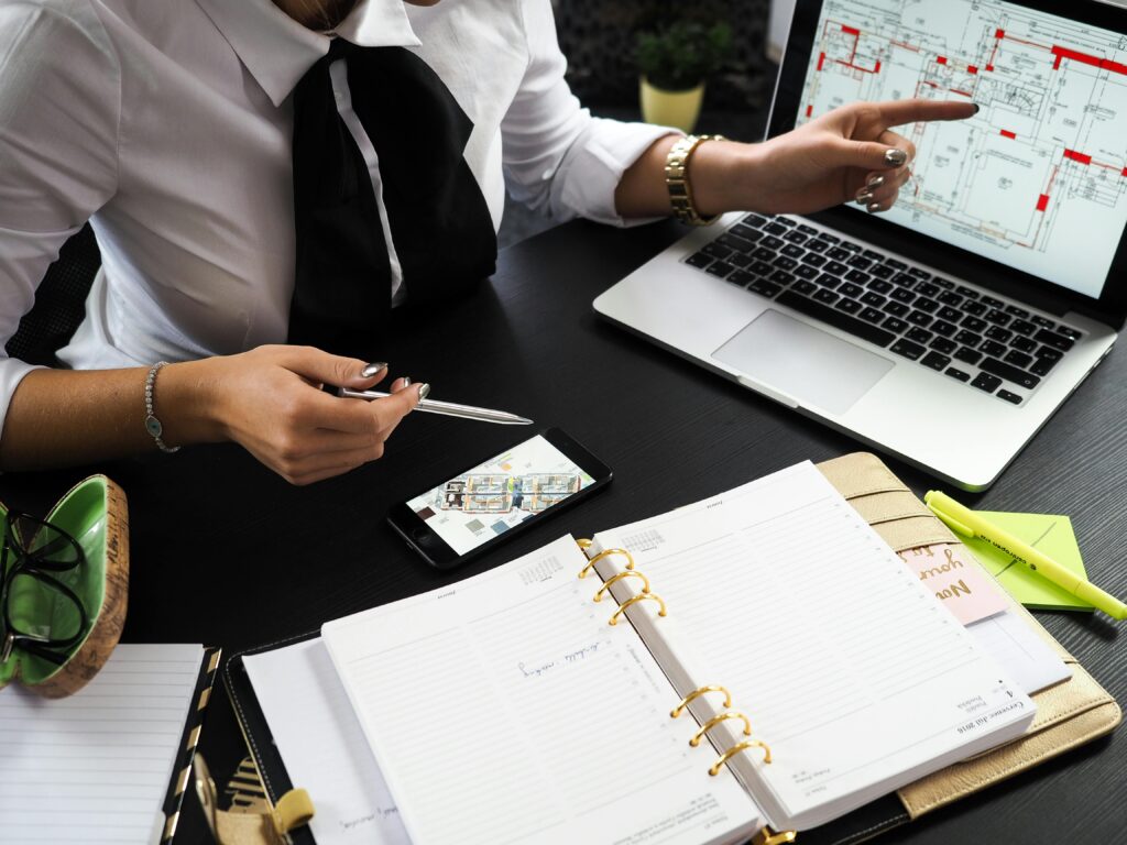 pexels-photo-313691-313691 A business professional working on real estate project plans using multiple devices in an office setting.